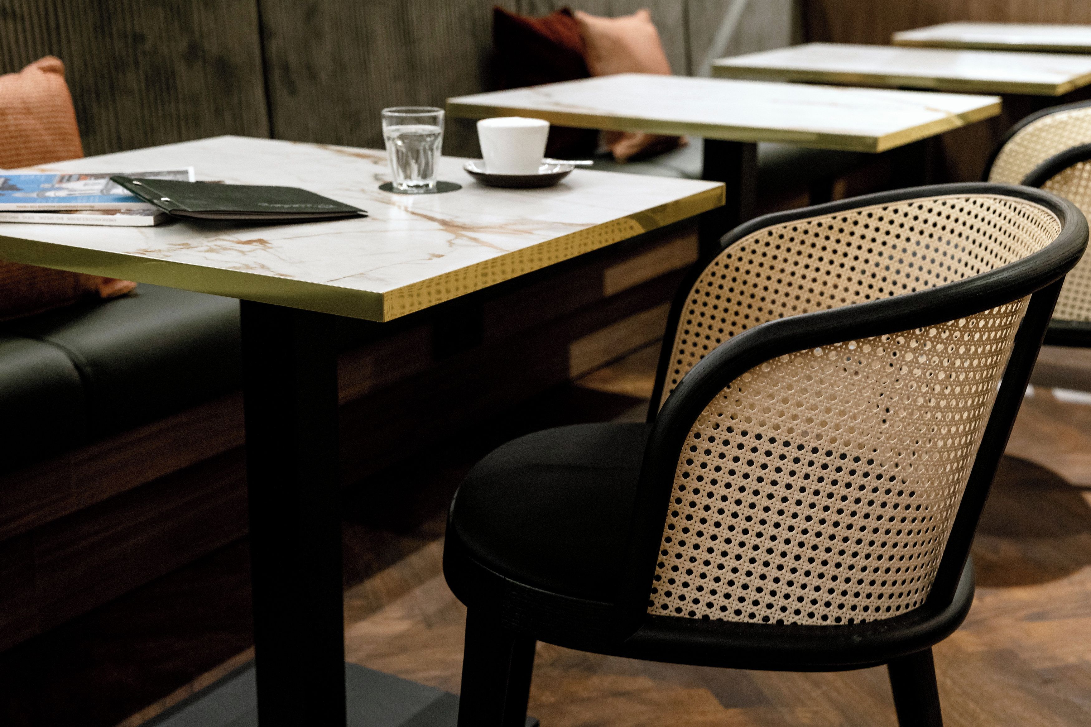 A restaurant interior with a booth seating arrangement, a table with a menu, a glass of water, and a cup.