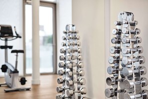 A gym with rows of dumbbells on racks, a stationary bike, and a treadmill. - MAXX by Steigenberger Vienna (Vienna)