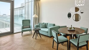 A modern living room with a sofa, chairs, a dining table, and a large window with a view. - MAXX by Steigenberger Vienna (Vienna)