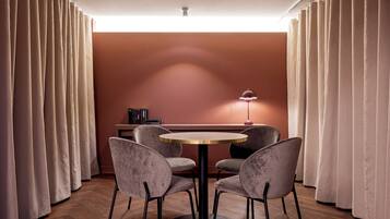 Una habitación con una mesa redonda, cuatro sillas, una lámpara y una estantería.