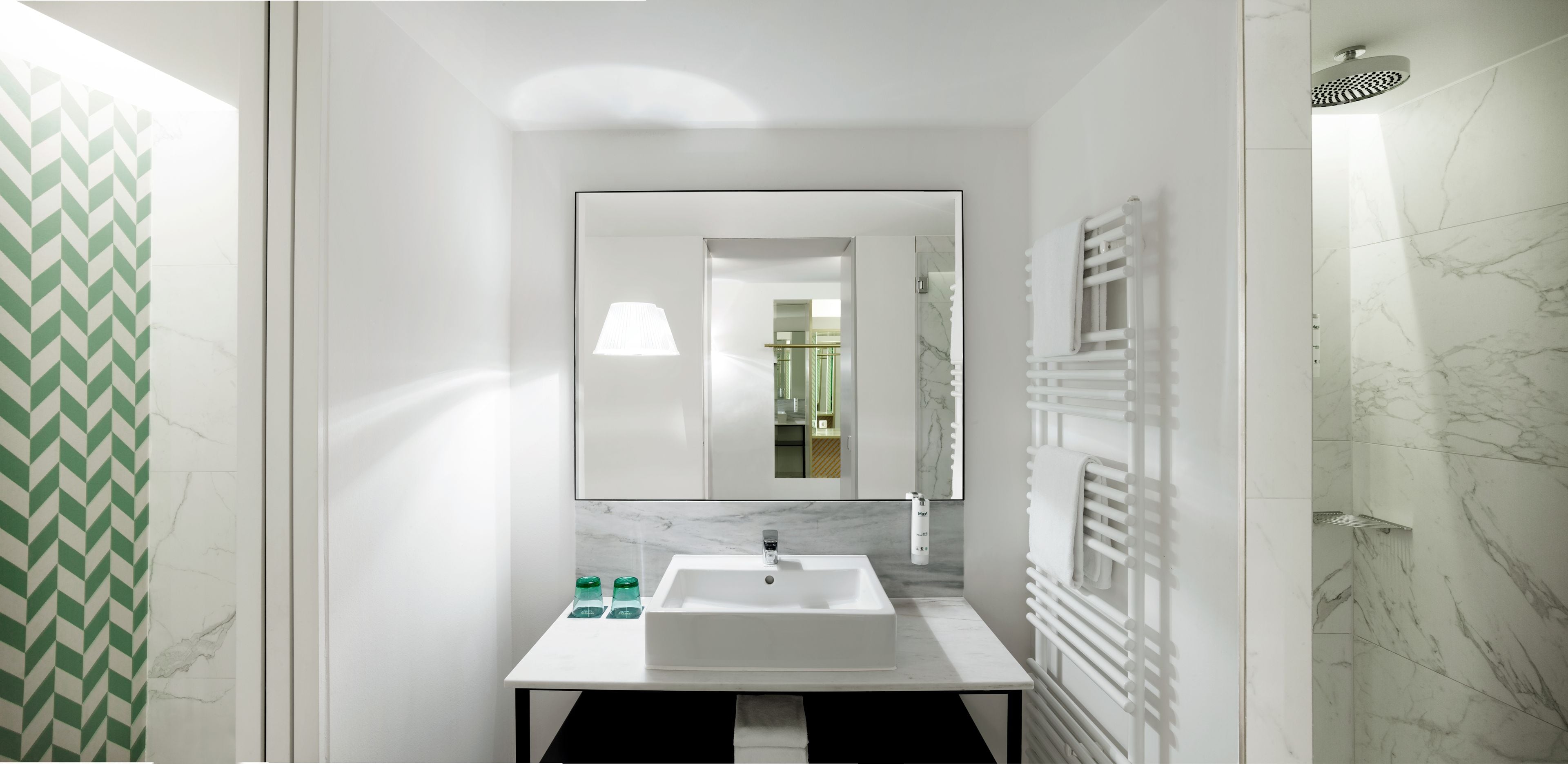 A modern bathroom with a white sink, mirror, and shower.