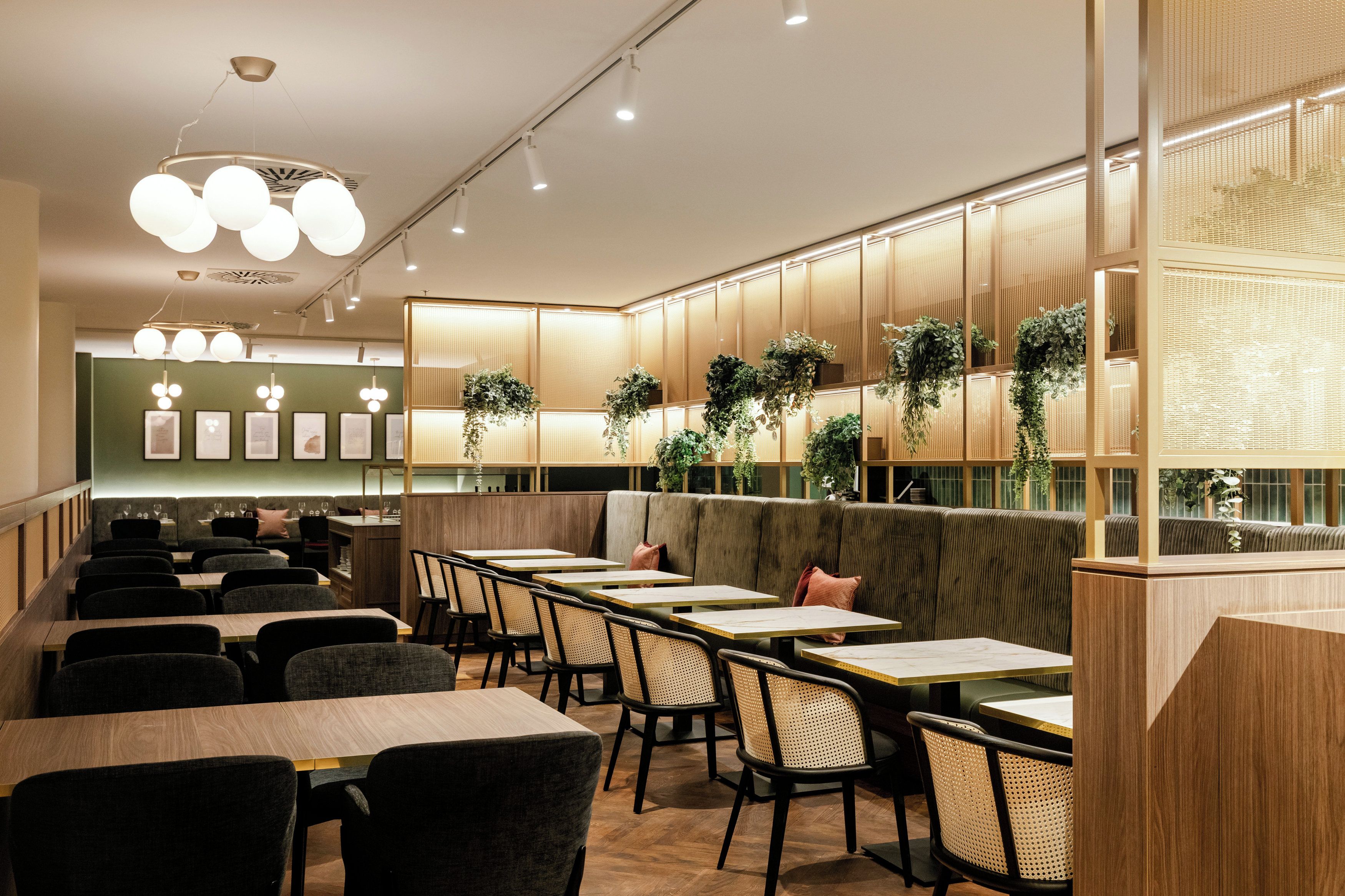 Interior de restaurante con cabinas, mesas y plantas colgantes.