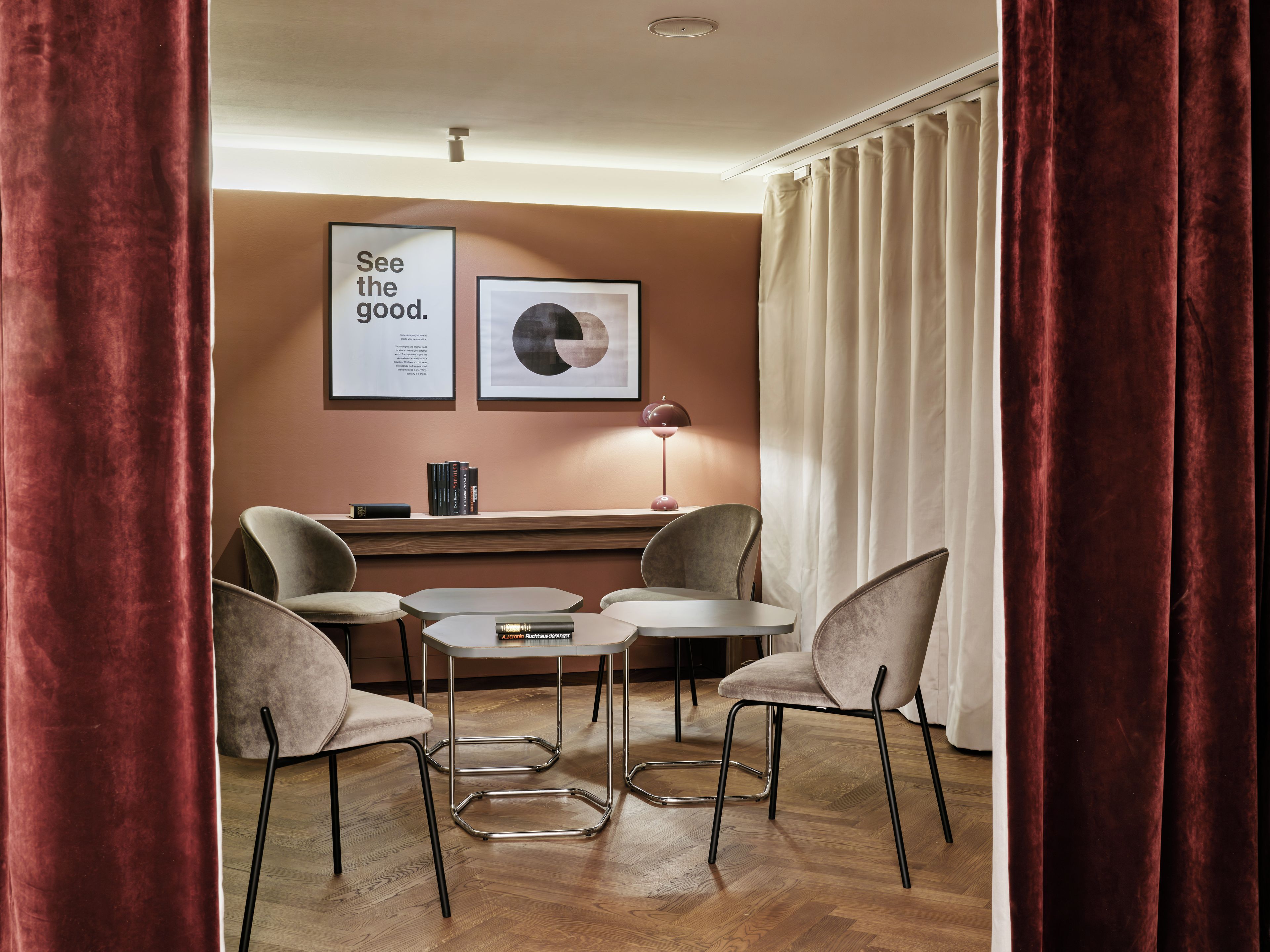 Una habitación moderna con una mesa redonda, dos sillas, una estantería y dos cuadros en la pared.