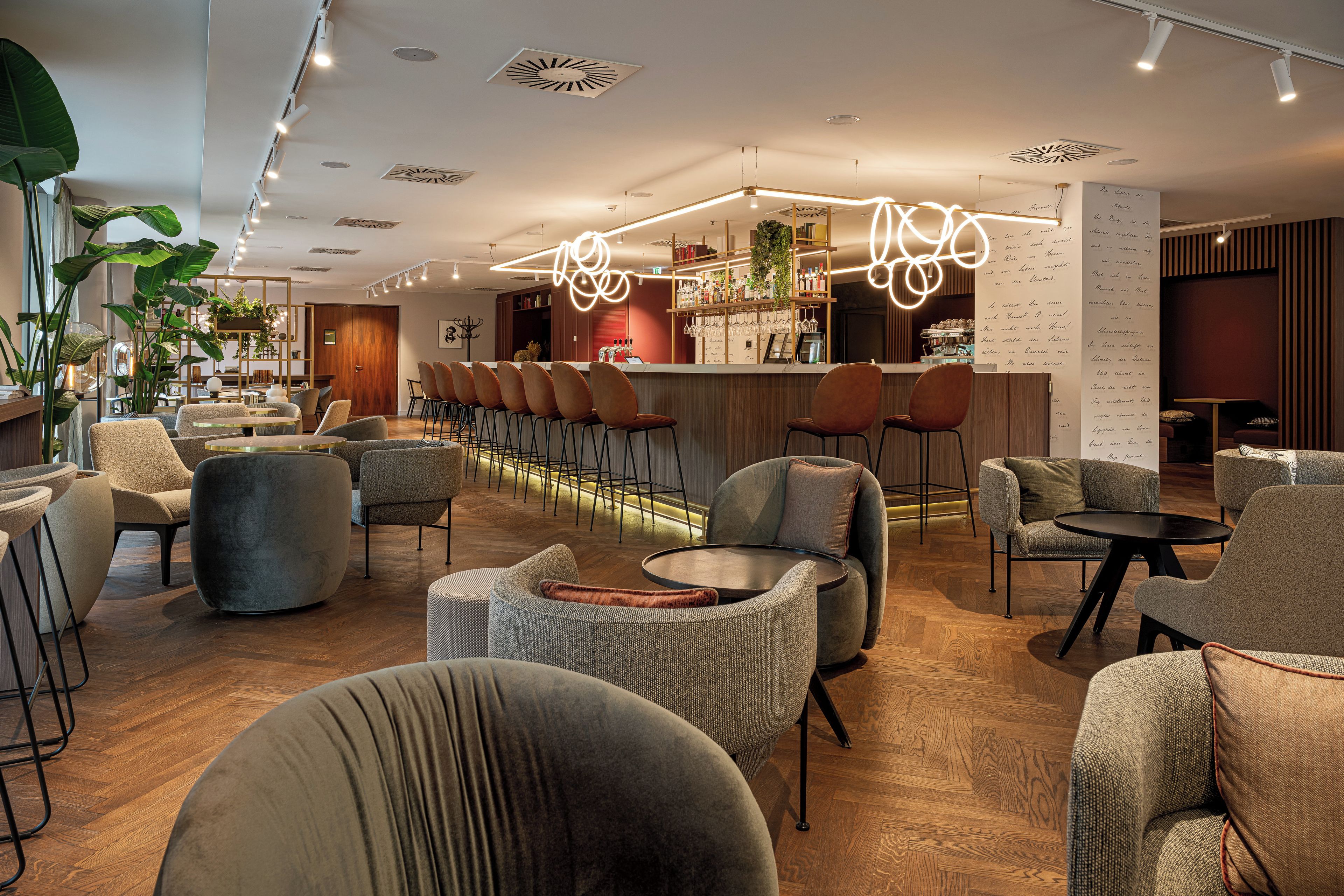 Un intérieur moderne avec un espace bar, des coins salon et une grande plante.
