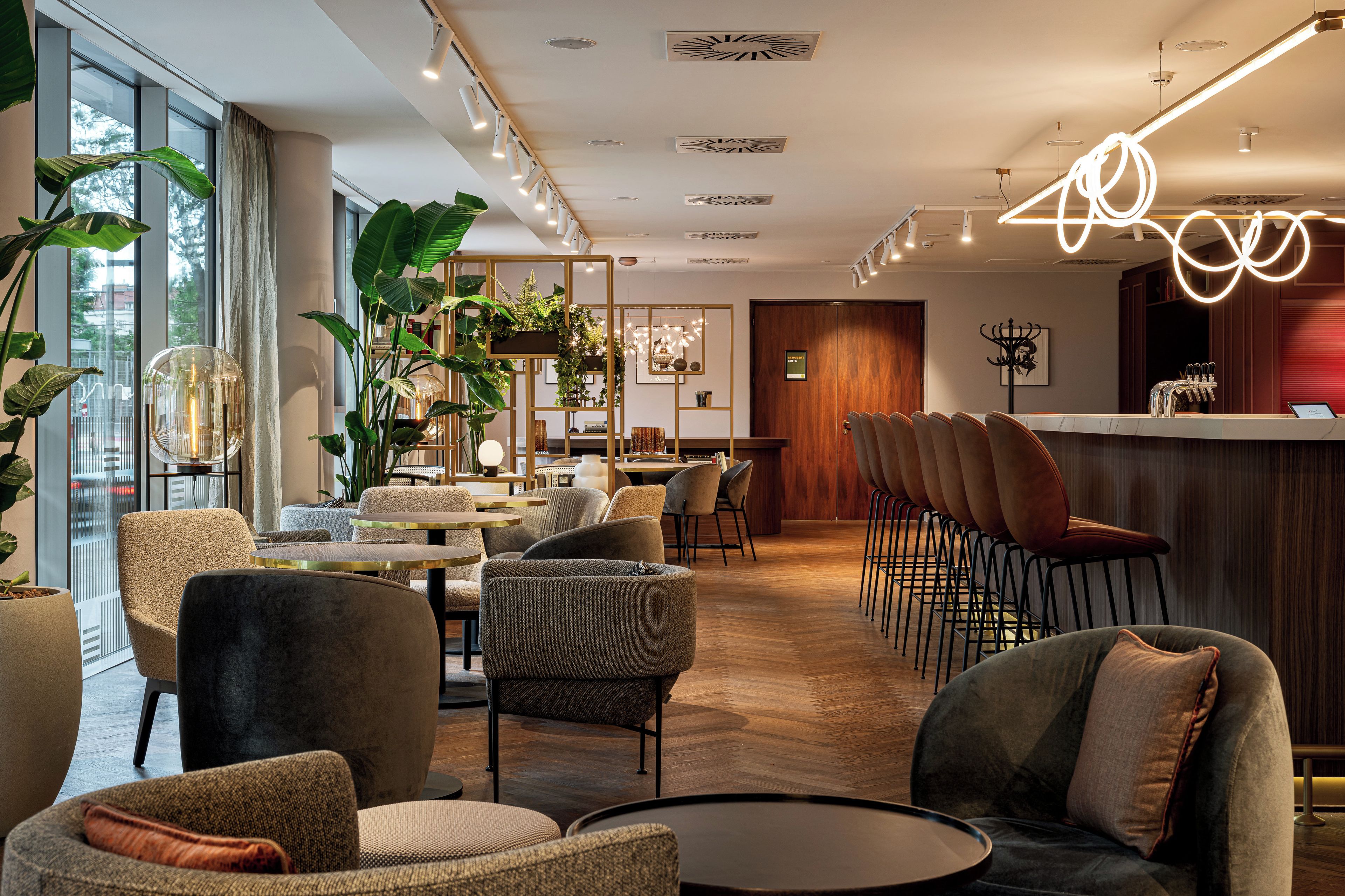 Un moderno vestíbulo de hotel con zonas de estar, un bar y amplias ventanas.