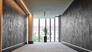 A modern hallway with concrete walls, large windows, and a central potted plant. - MAXX by Steigenberger Vienna (Vienna)