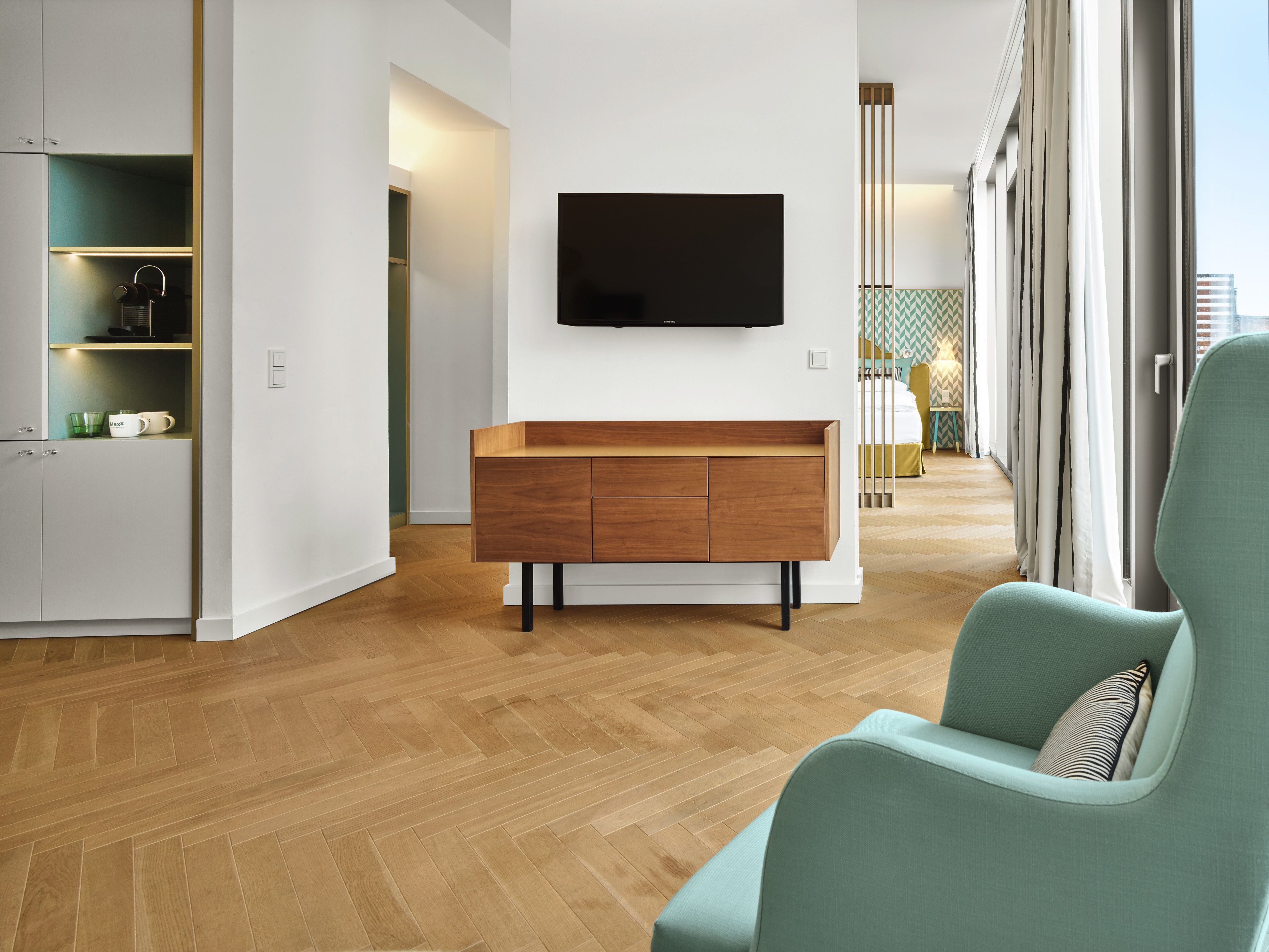 A modern living room with a wooden cabinet, a flat-screen TV, and a green armchair.