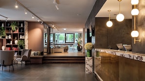 A modern interior with a reception desk, seating area, and a view through a glass door. - Crowne Plaza Vienna by IHG (Vienna)