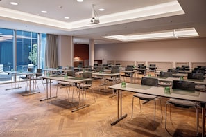 A conference room with multiple tables, chairs, and a large projection screen. - Crowne Plaza Vienna by IHG (Vienna)