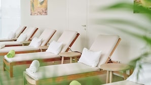 A row of sun loungers with white cushions and green towels, wooden side tables, and a painting on the wall. - Crowne Plaza Vienna by IHG (Vienna)