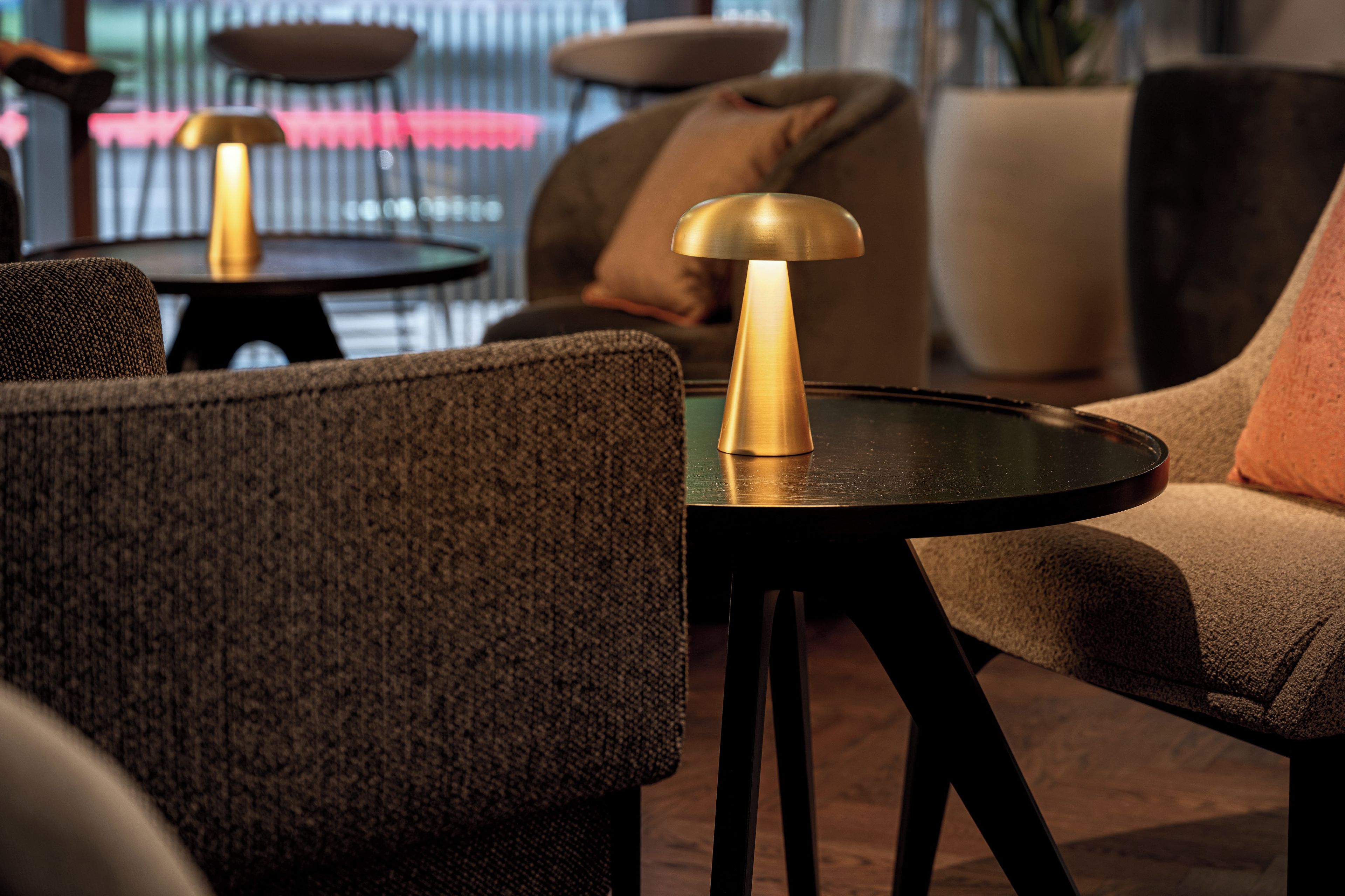 A modern lounge area with sofas, tables, and lamps.