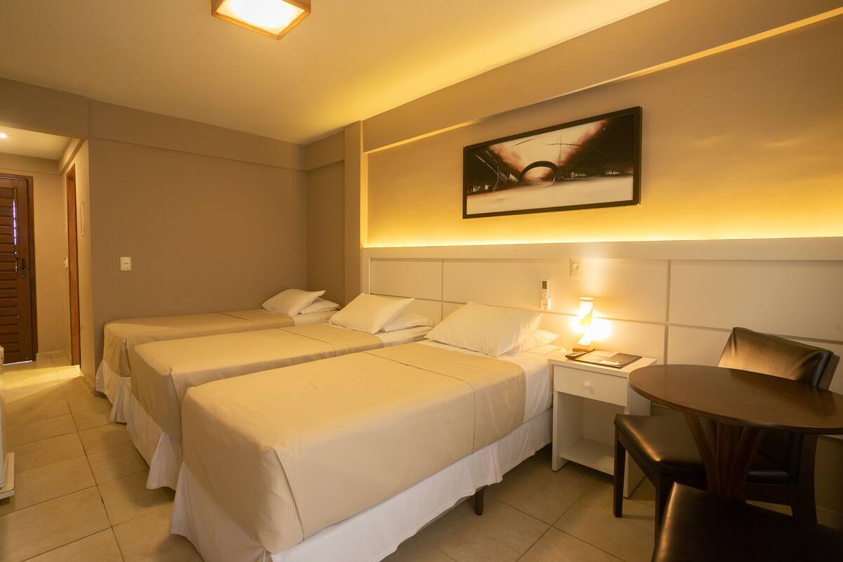 Ein Hotelzimmer mit zwei Betten, einem kleinen Tisch mit Stuhl, einem Nachttisch und einem Wandbild.