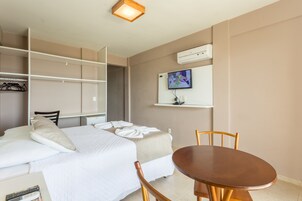 Une chambre d’hôtel avec un lit, un bureau, une chaise, une télévision et une petite table.