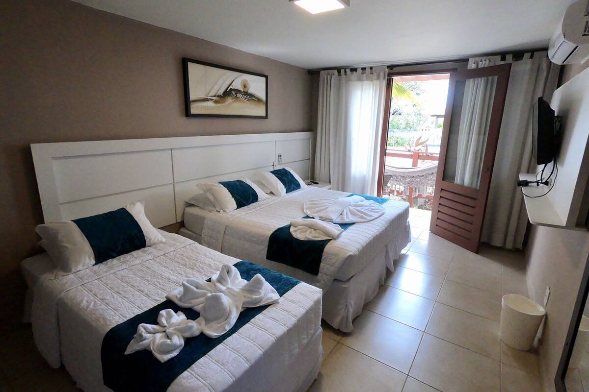 Ein Hotelzimmer mit zwei Betten, einem Bild an der Wand, einem Fernseher und Blick ins Freie.