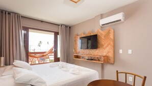 Ein Hotelzimmer mit Bett, einem an einer Wand mit Fischgrätmuster befestigten Fernseher, einem Esstisch und einer Klimaanlage.