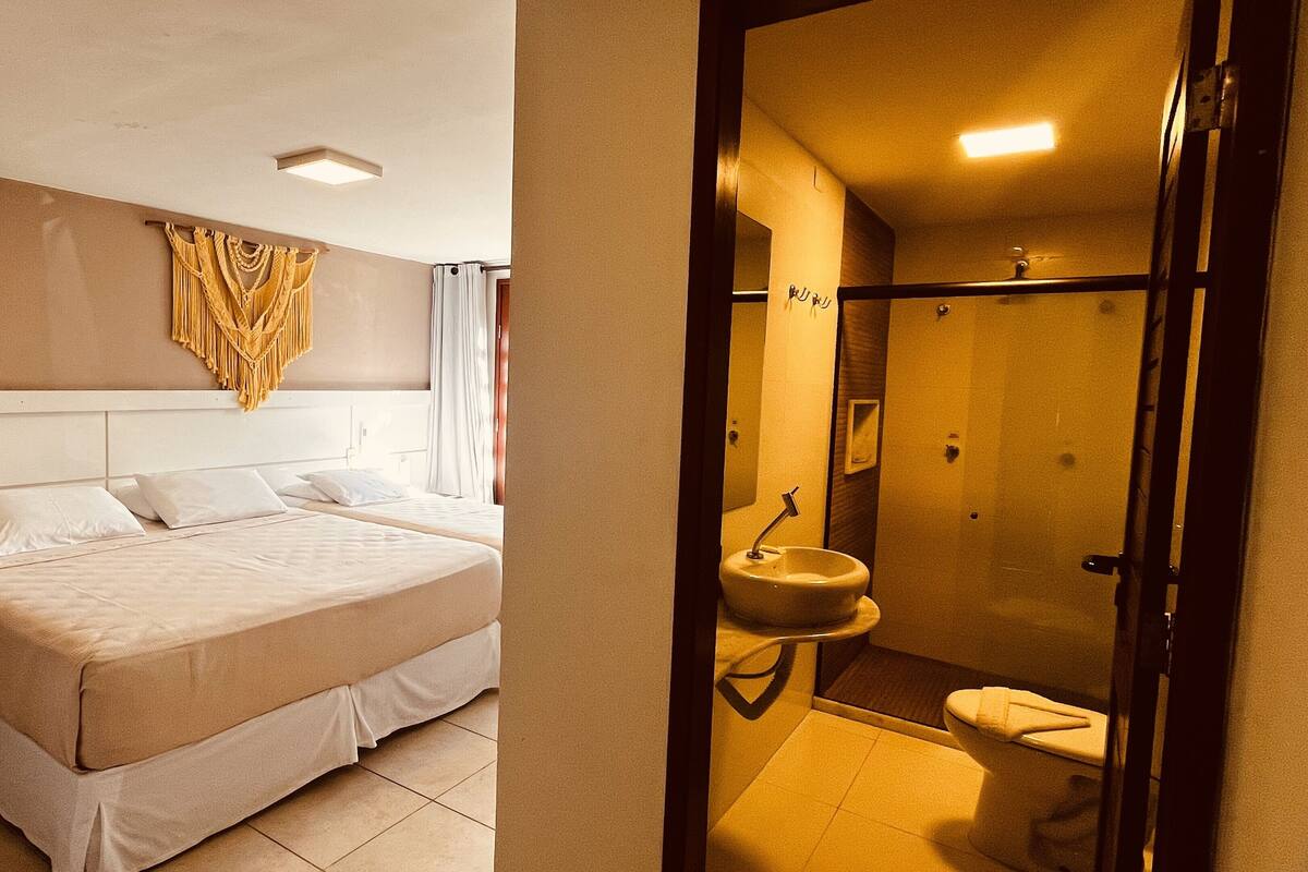 Ein Hotelzimmer mit einem großen Bett, einem Wandbild und einem Badezimmer mit Waschbecken und Toilette.