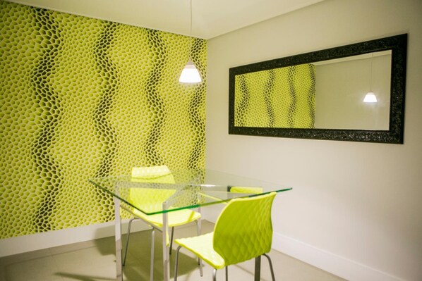 Un comedor moderno con una mesa y sillas de vidrio, una pared texturizada y un espejo.