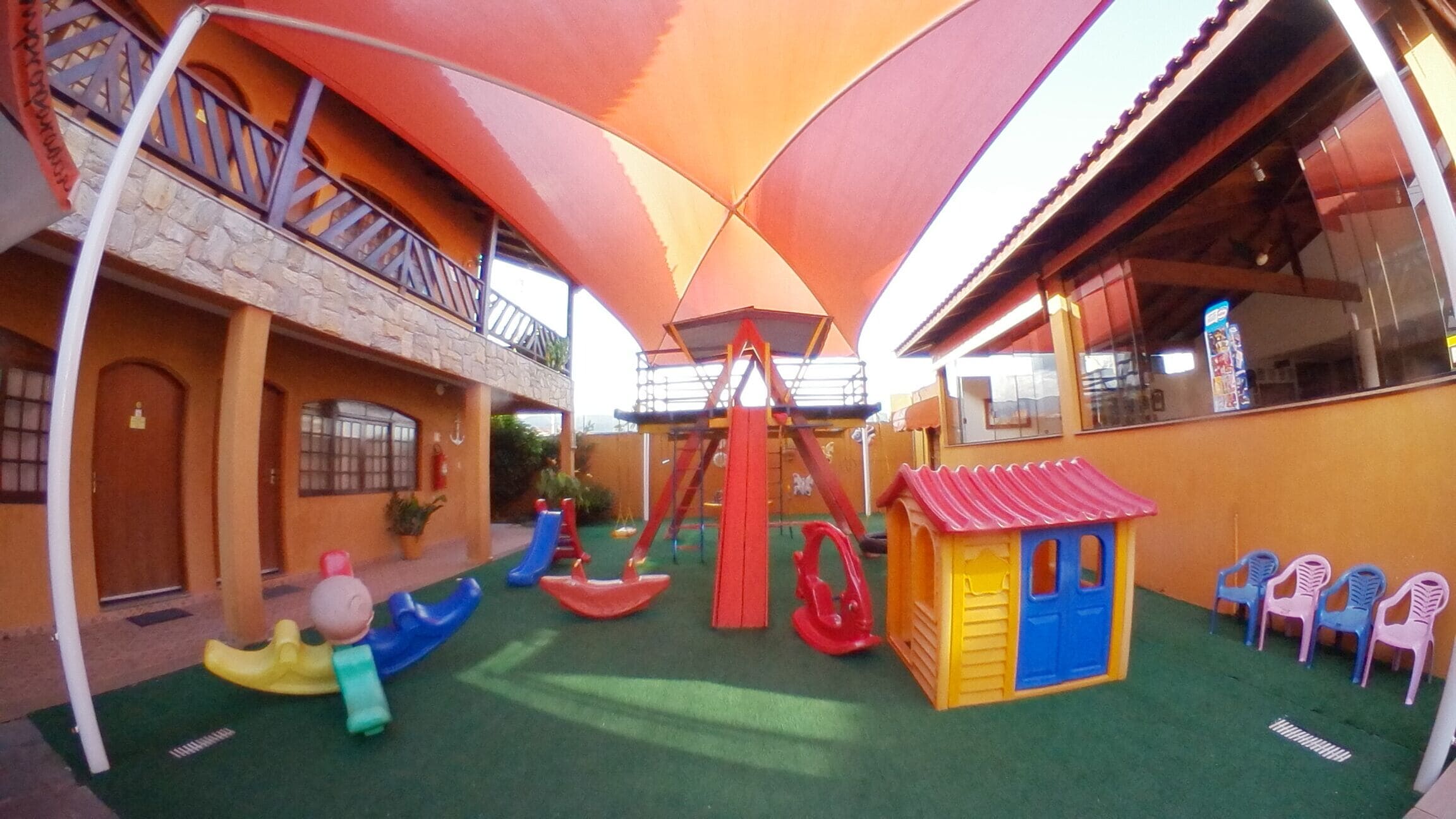 A children's play area with slides, swings, and a small house.