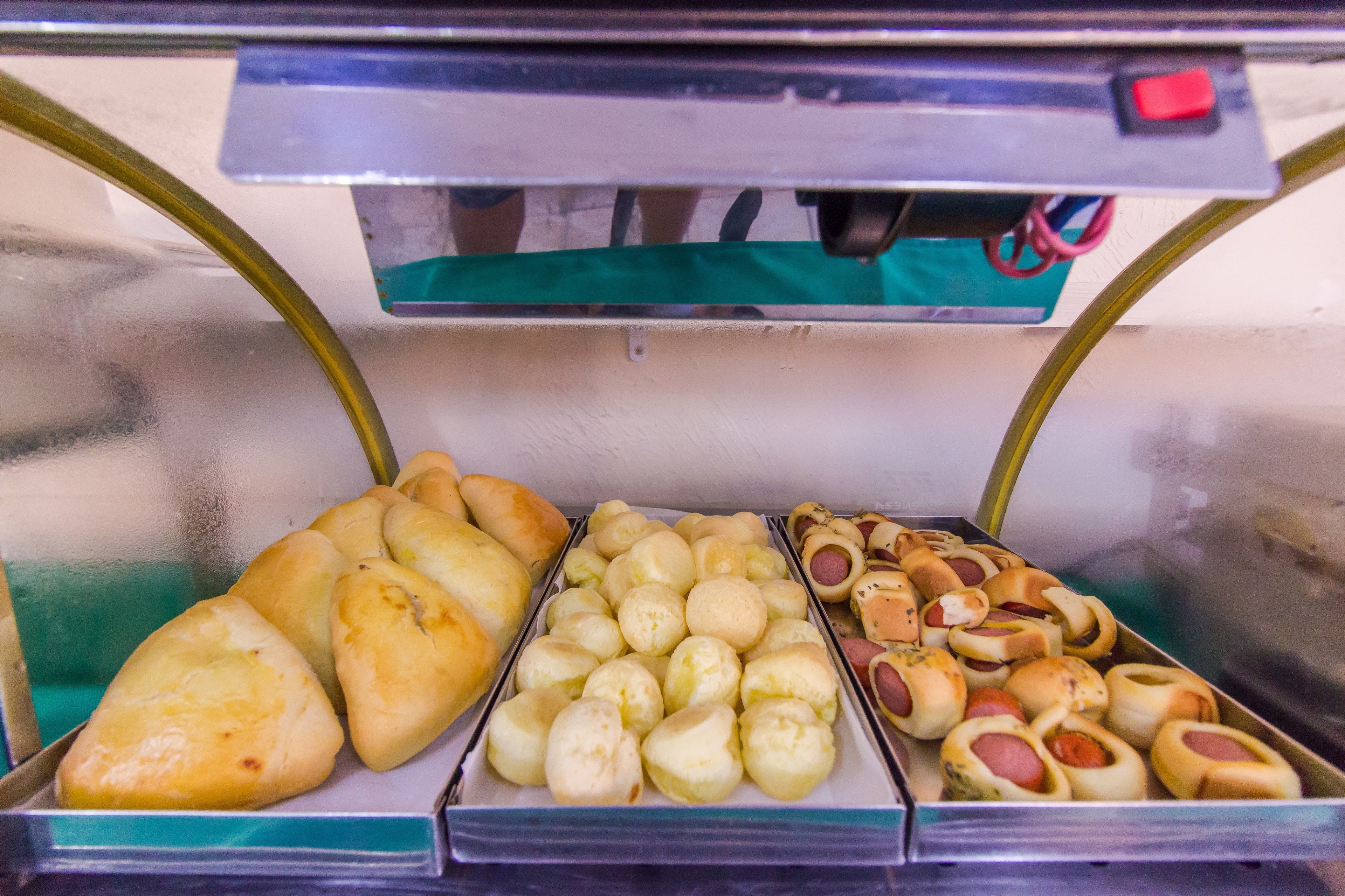 Een vitrine met diverse gebakken producten, waaronder brood en hotdogs.