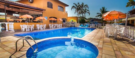 Een buitenzwembad, parasols bij het zwembad en ligstoelen