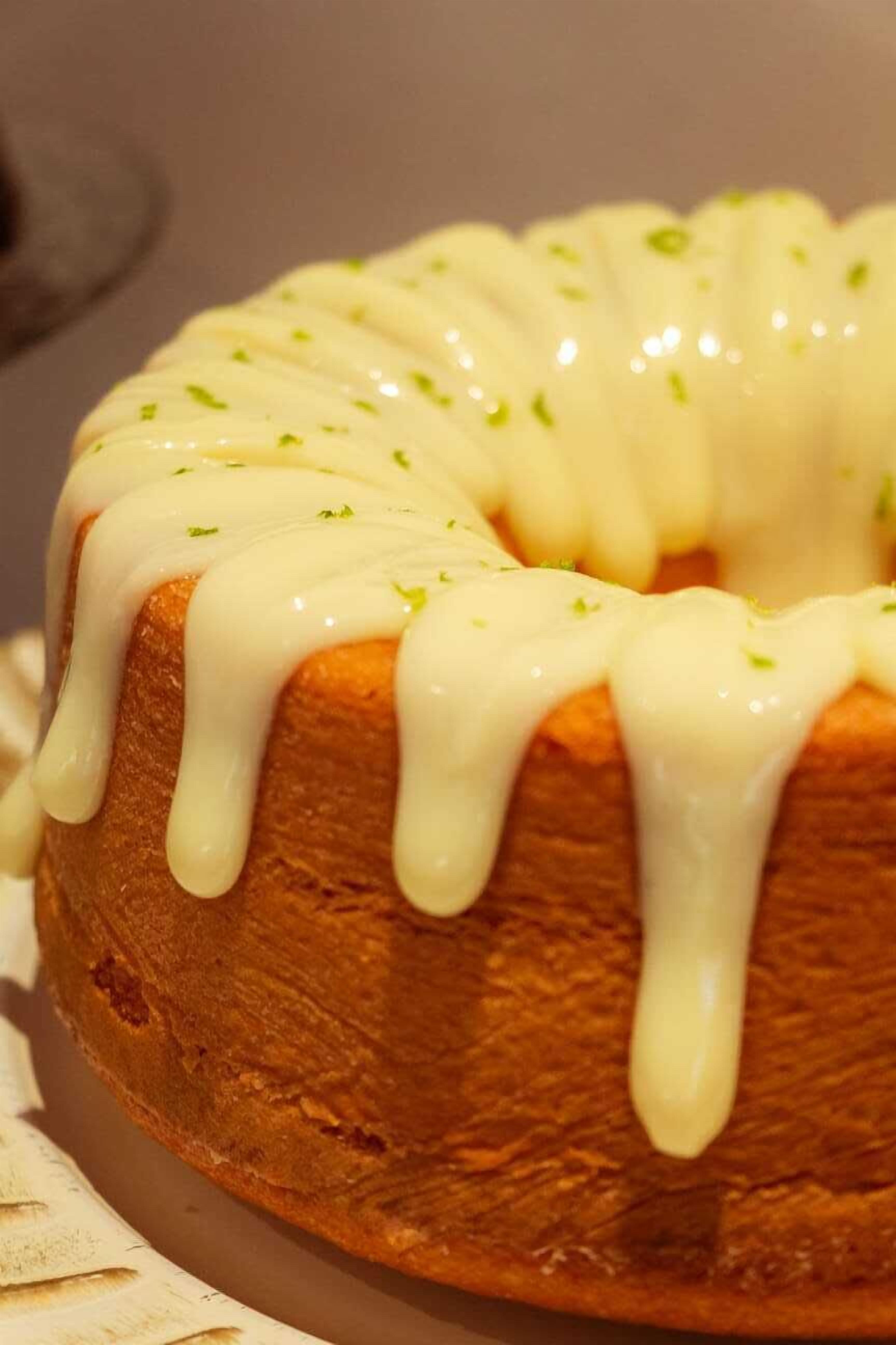 A bundt cake with white icing and green garnish.
