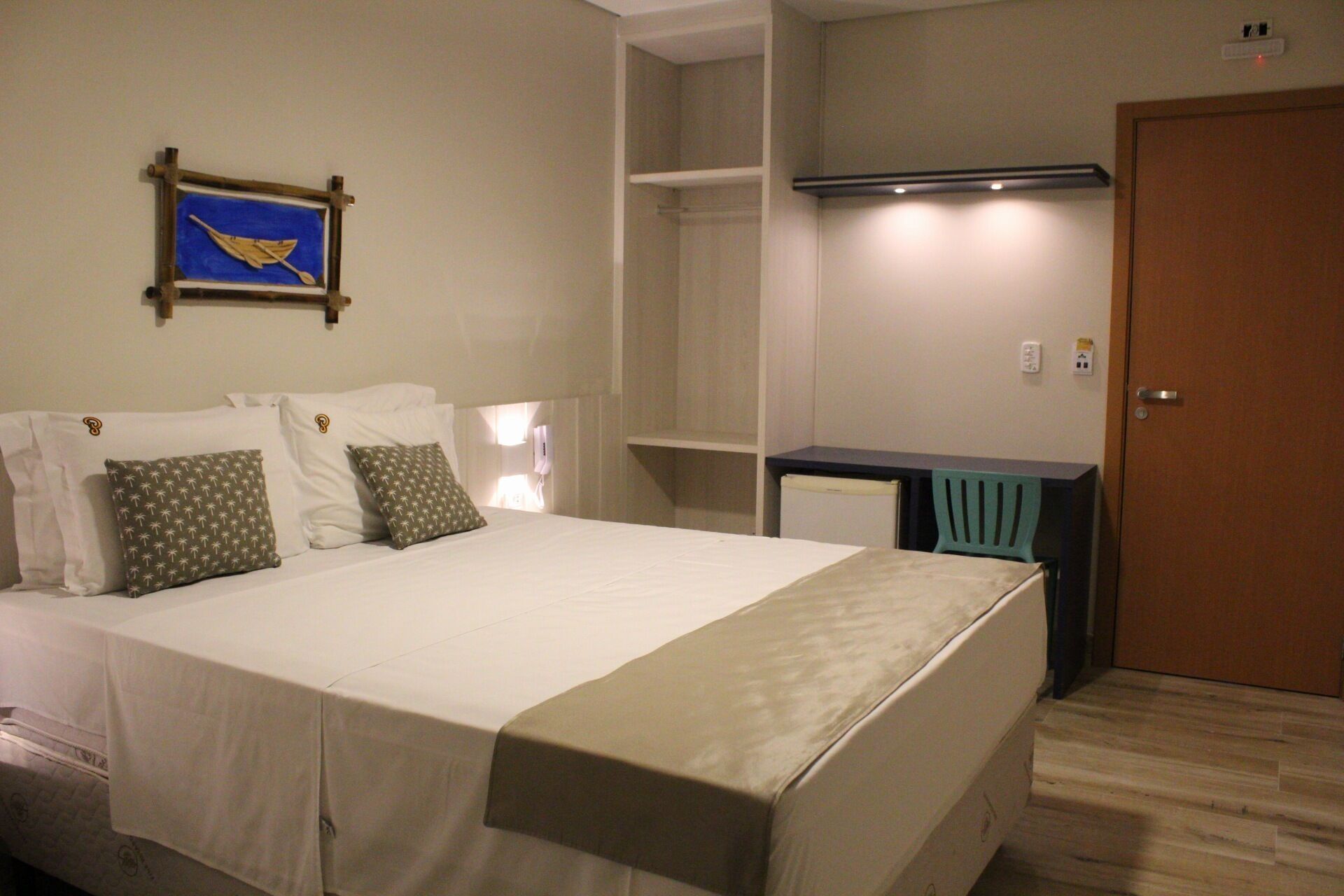 A neatly arranged bedroom with a bed, bedside tables, a desk, and a wardrobe.