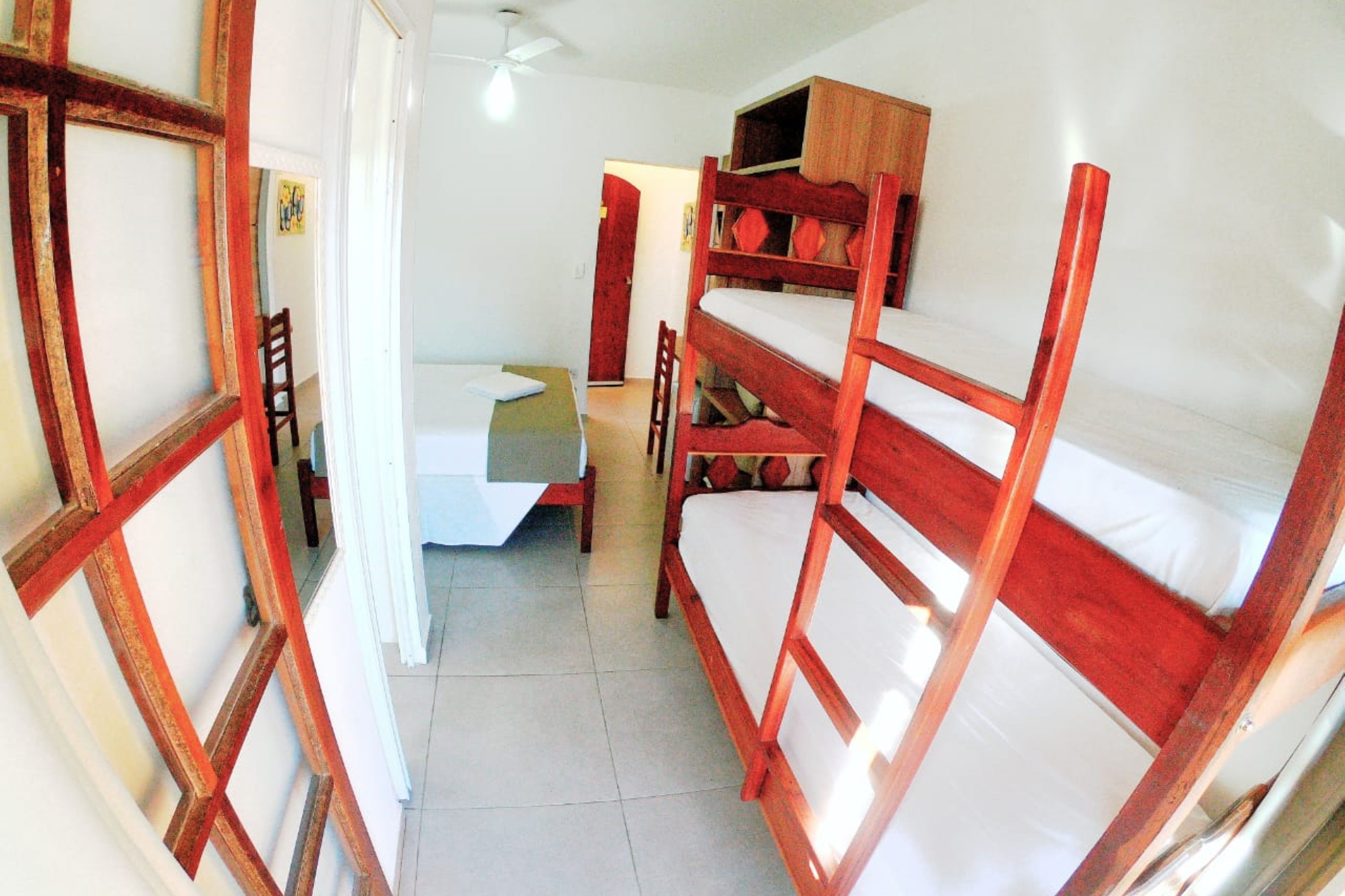 A dormitory room with bunk beds, a desk, and a chair.