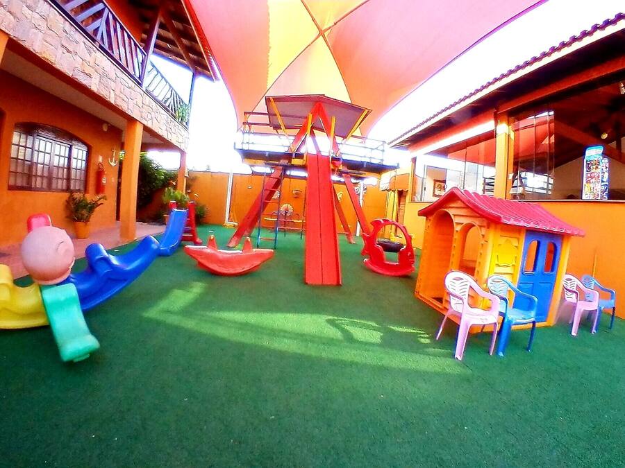 Un'area giochi per bambini con scivoli, altalene e una casetta.
