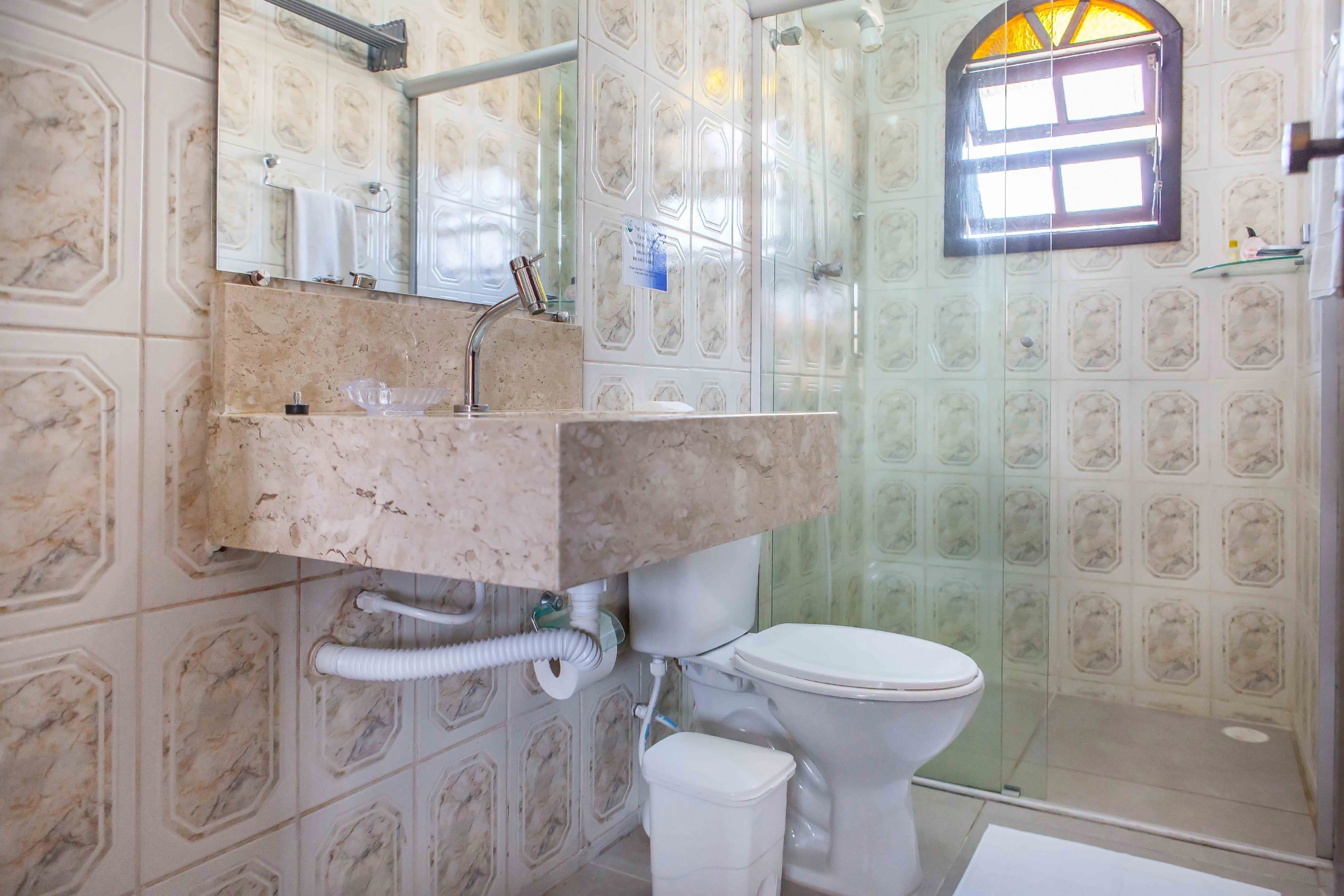A bathroom with a marble sink, a toilet, and a shower area.