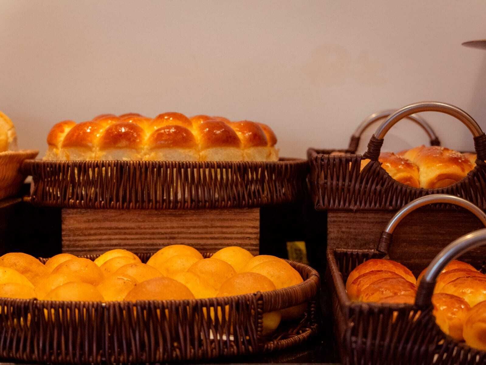 Cestas de mimbre llenas de panecillos y naranjas.