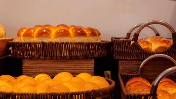 Cestas de mimbre llenas de panecillos y naranjas.