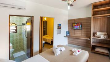 Quarto de hotel com cama, guarda-roupa, zona de duche e televisão.