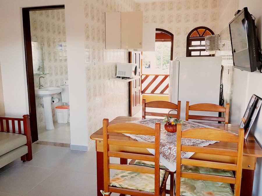 A dining area with a wooden table, chairs, and a television mounted on the wall.