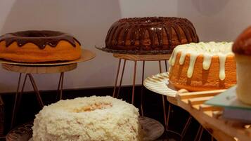 A variety of cakes on display, including a bundt cake, a cake with white icing, and a cake with chocolate drizzle.