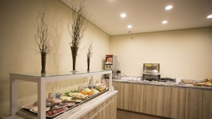 A buffet area with various food items, a coffee machine, and decorative branches. - Druds Hotel Hortolândia (Hortolandia)