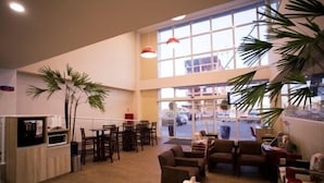 A spacious indoor area with high ceilings, large windows, and multiple seating arrangements. - Druds Hotel Hortolândia (Hortolandia)
