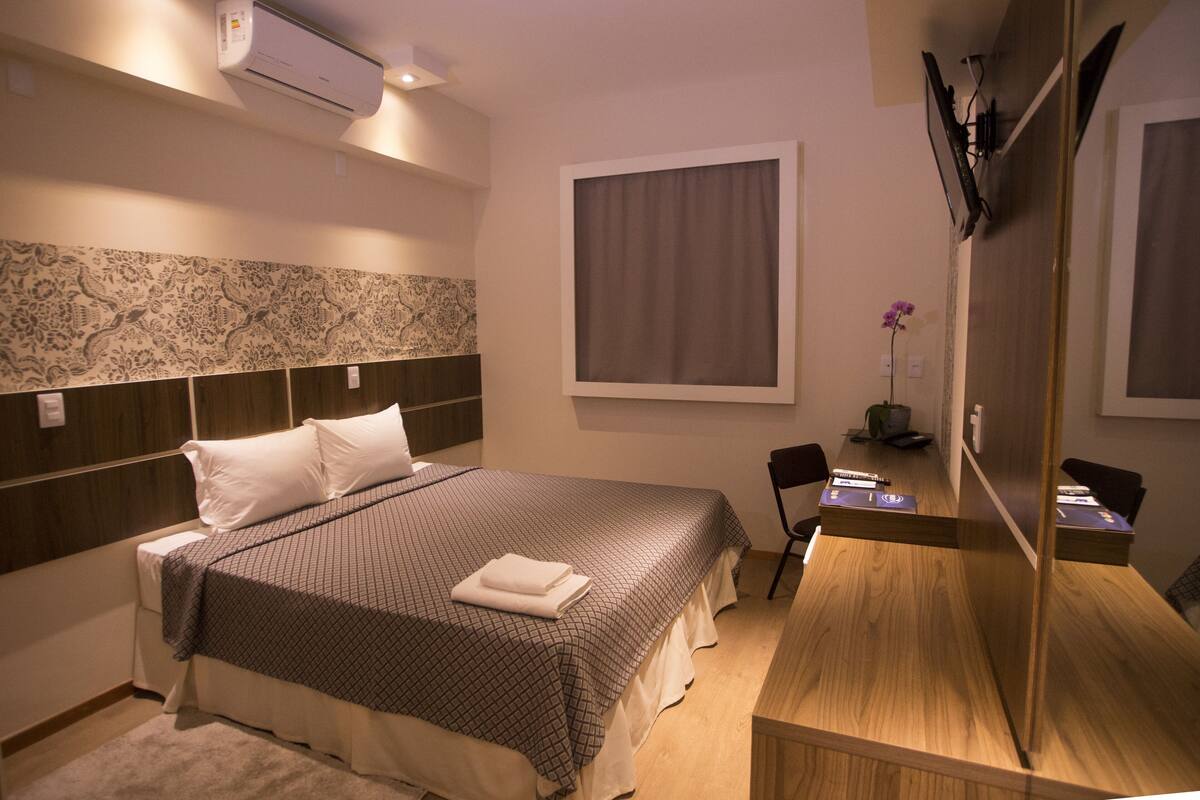 Une chambre d’hôtel avec un grand lit, un bureau et un miroir.