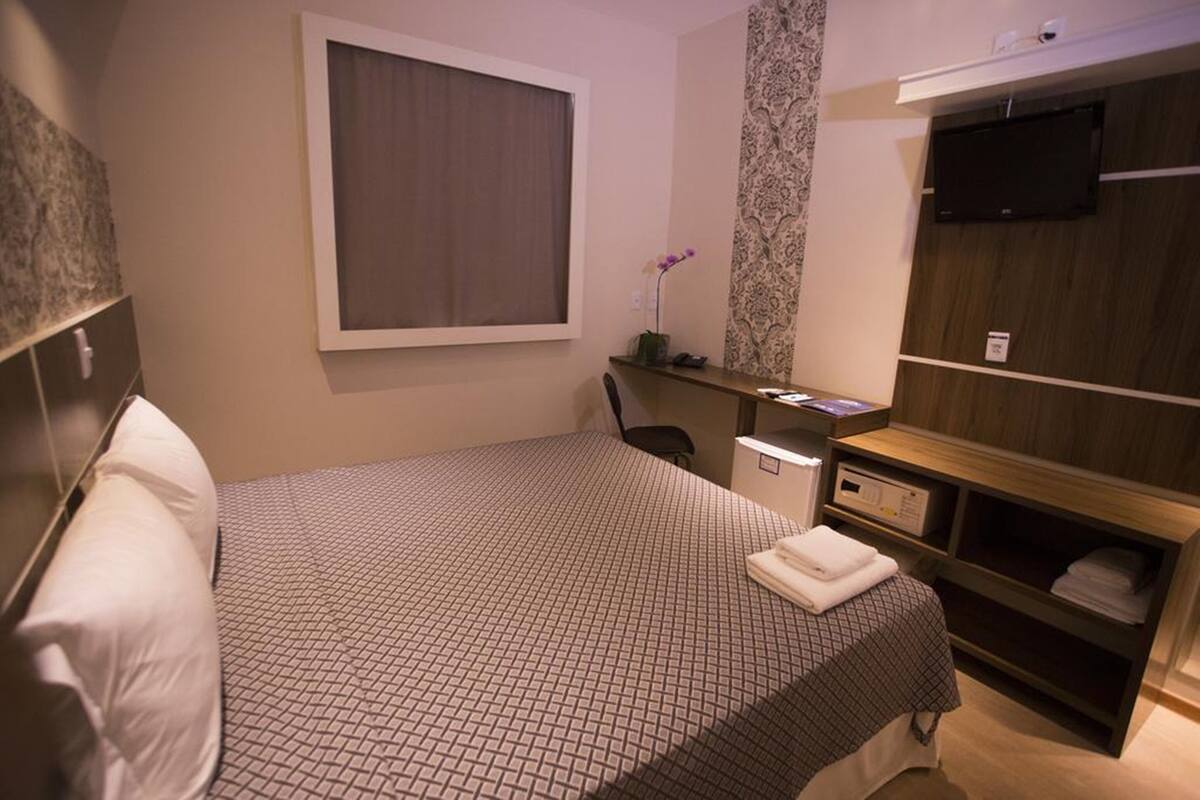 Une chambre d’hôtel équipée d’un lit, d’un bureau, d’une chaise, d’une télévision et d’une armoire.