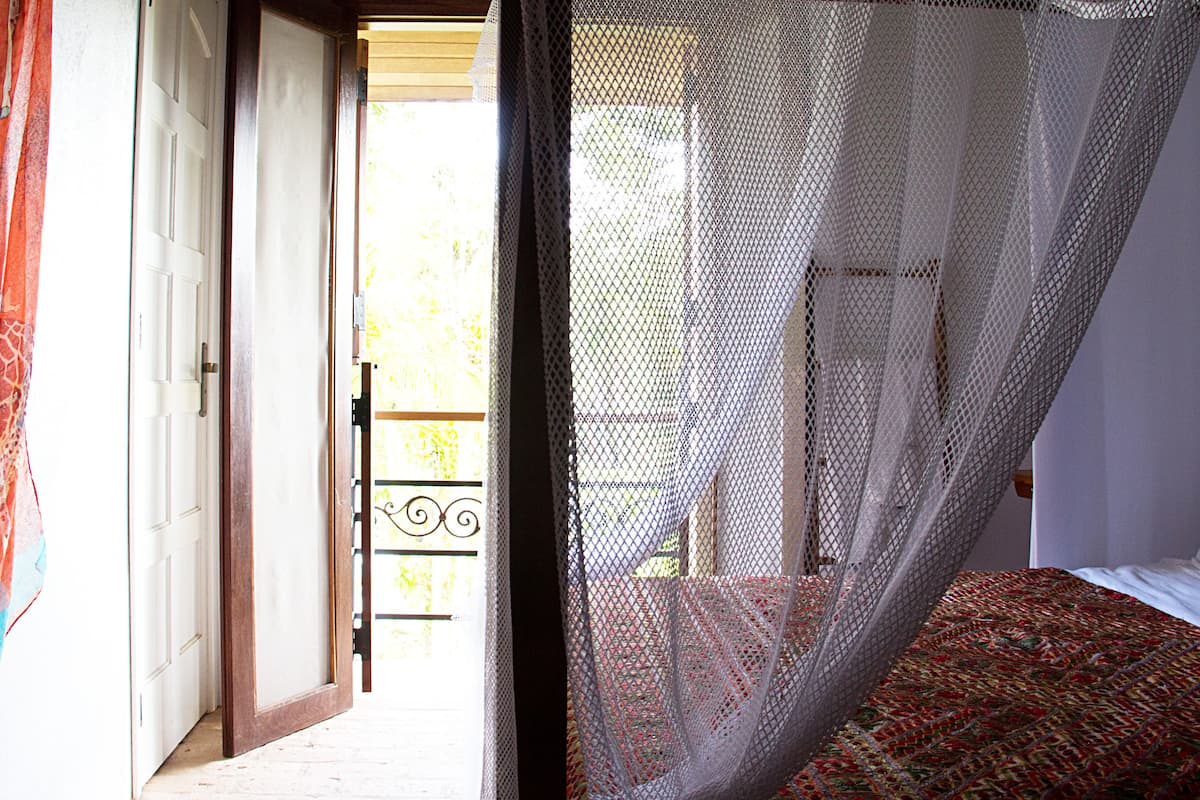 A room with a bed, a door, and a balcony with a metal railing.