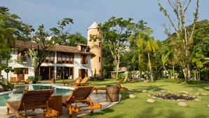 Ein Resort mit Schwimmbad, Liegestühlen und einem Turm.