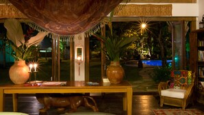 Ein Zimmer mit großem Fenster mit Blick auf einen Pool, einem Holztisch mit Kerzen und einem Stuhl.