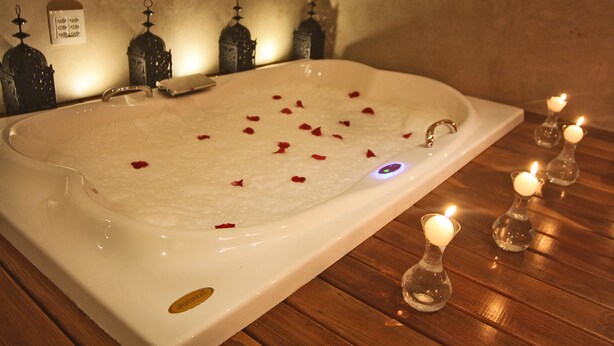 Una bañera grande con pétalos de rosa y velas.