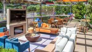 Un patio exterior con televisor, asientos y una fogata.