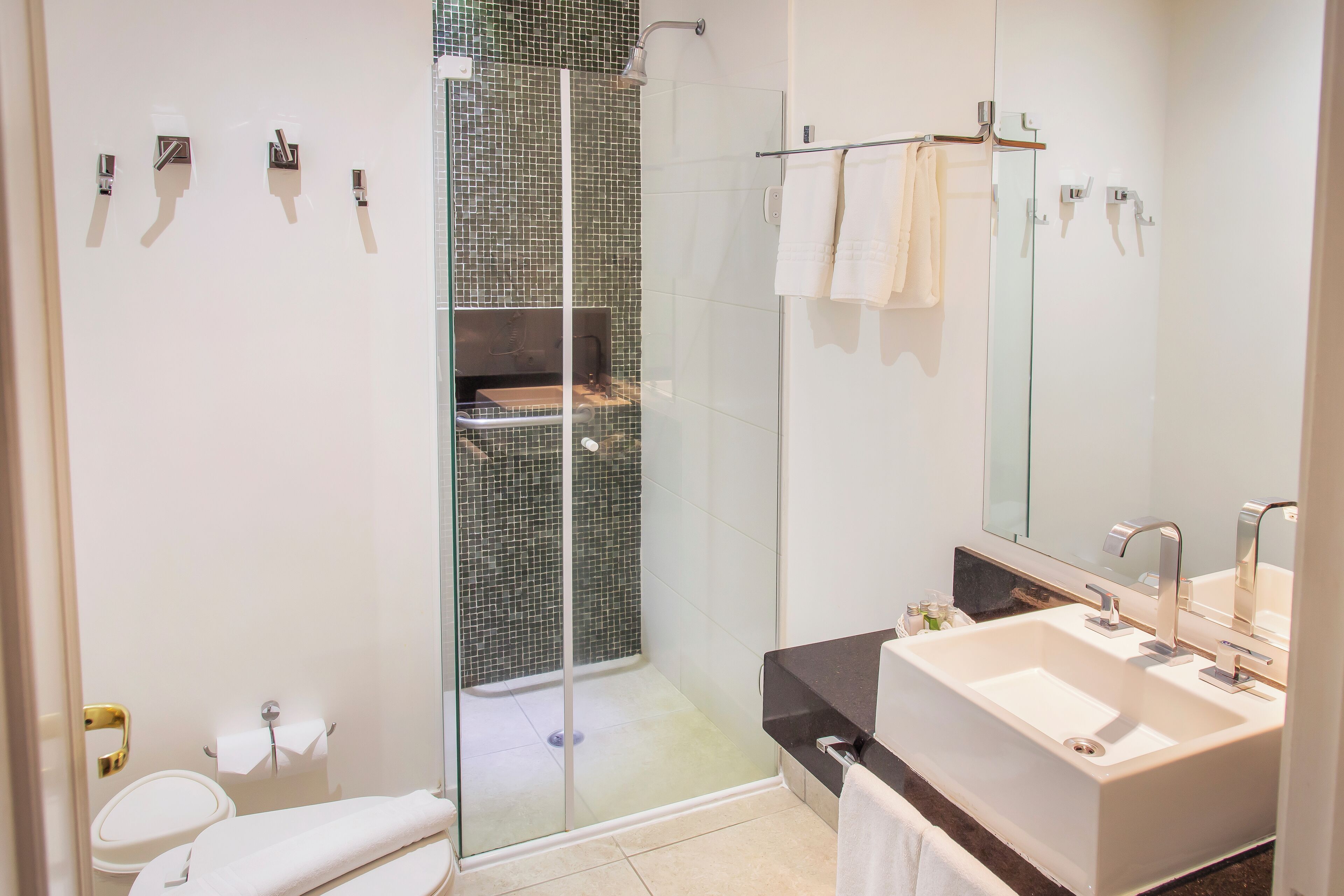 A modern bathroom with a glass-enclosed shower, a large sink, and a mirror.