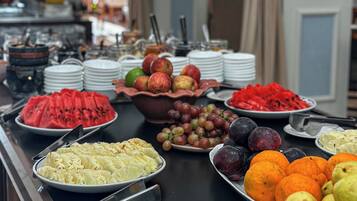 A buffet with various fruits and vegetables, including watermelon, grapes, and oranges.
