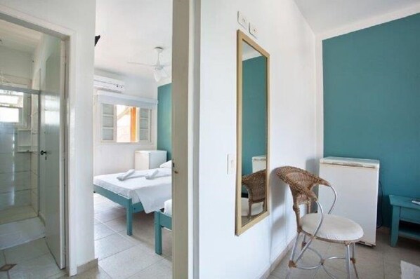Una habitación con una cama, una silla, un espejo y una mesita.