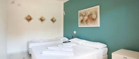 A hotel room with two beds, a teal accent wall, and a painting.