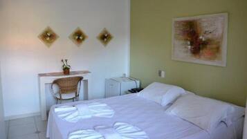 A bedroom with a bed, a desk, a chair, and a small table.