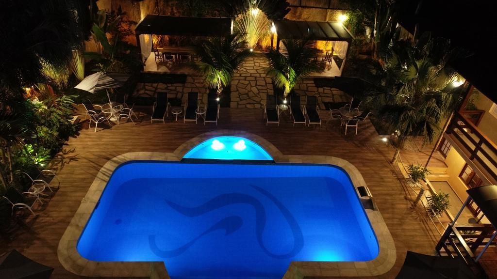 An outdoor swimming pool with a stone wall and lounge chairs.