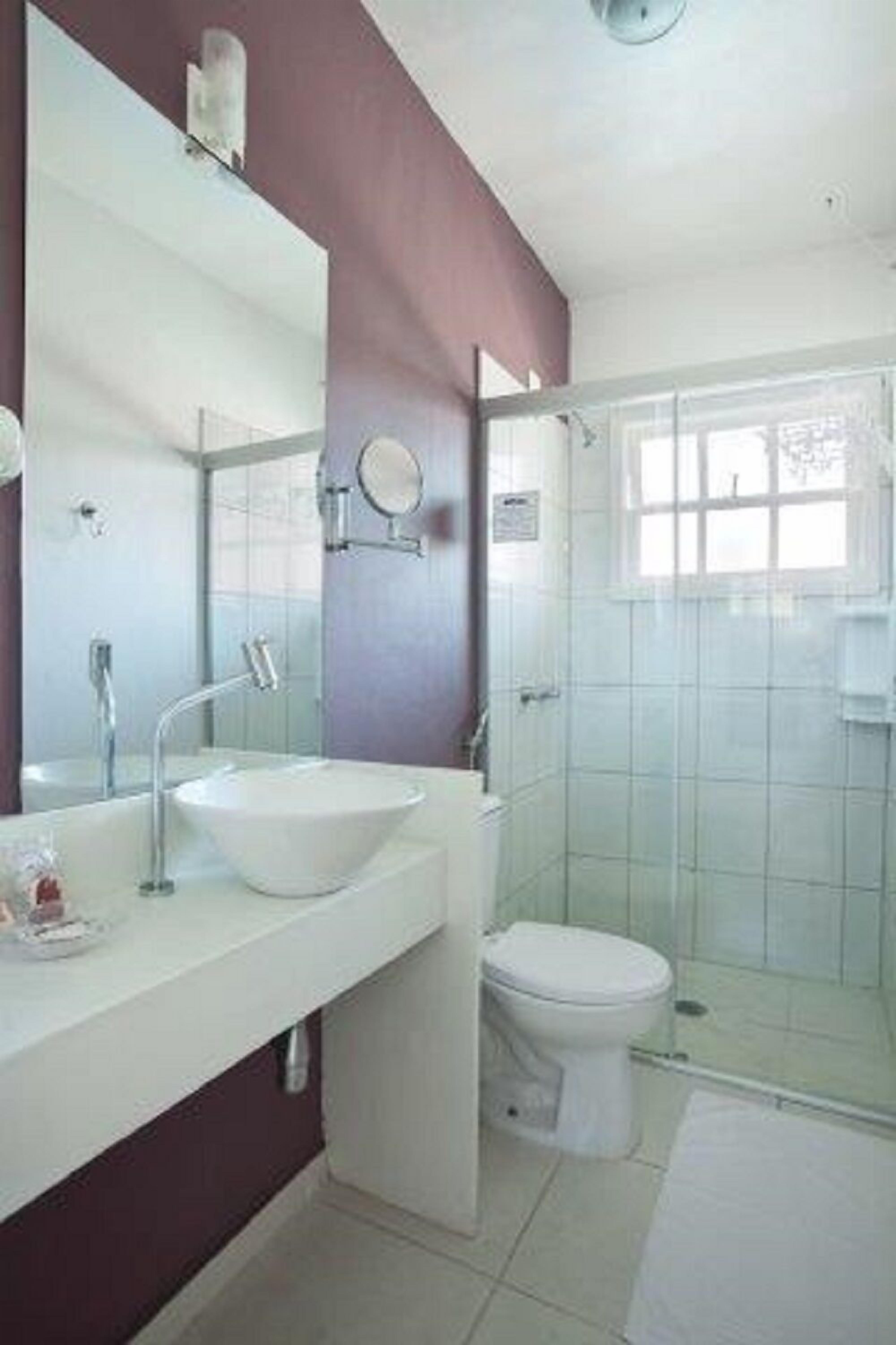 A modern bathroom with a white sink, mirror, and toilet.